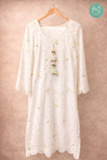 White lace dress with floral embroidery on a wooden hanger against a beige background